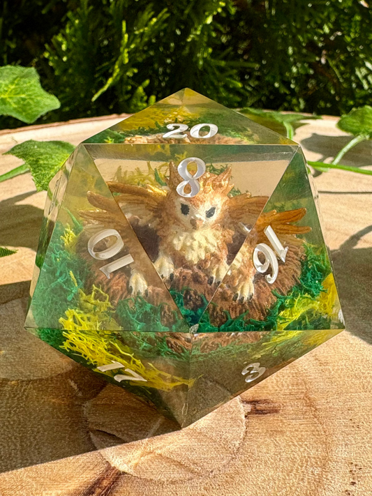D20 polyhedral dice with a baby griffon with greenery in the background