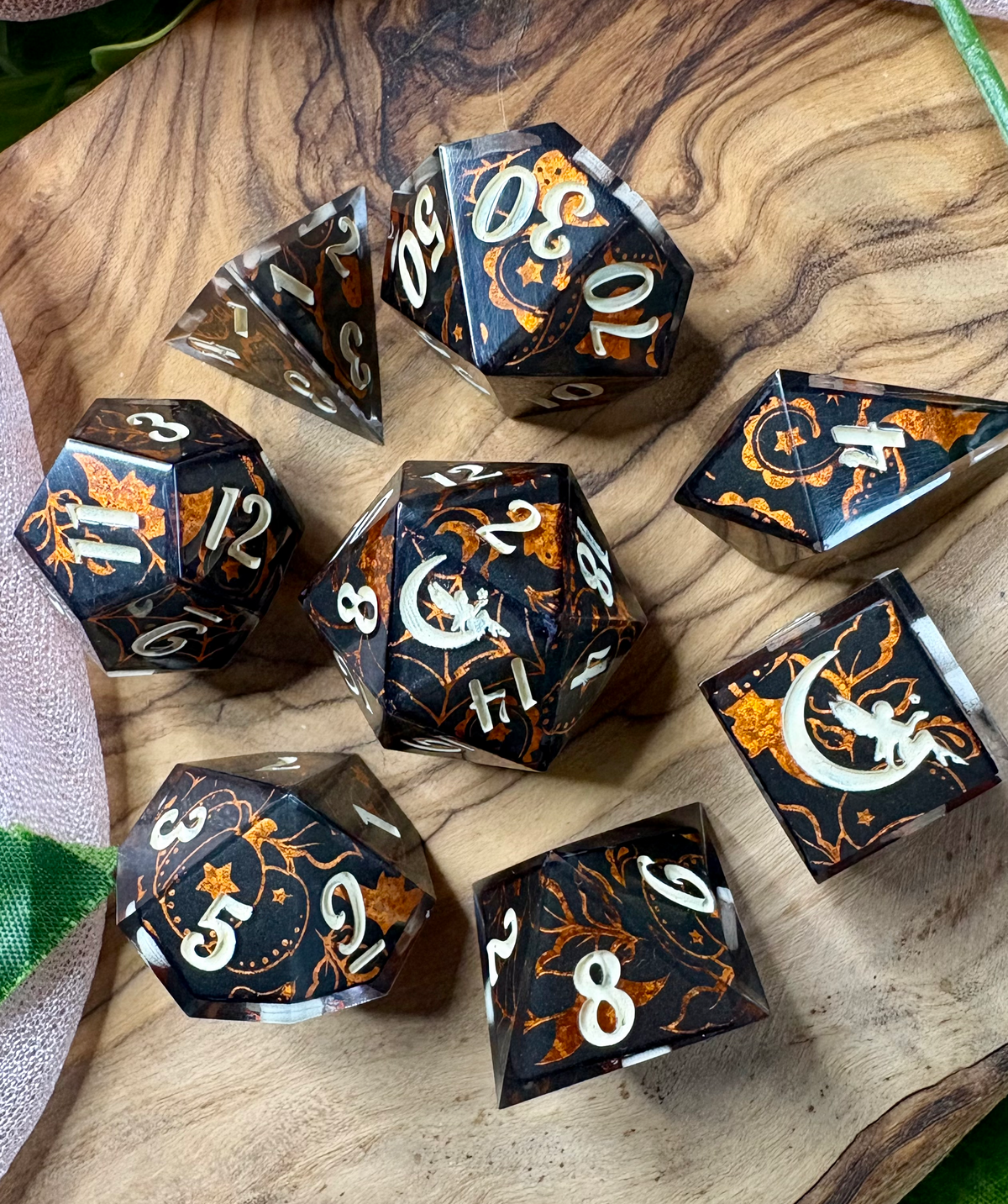 a set of black polyhedral dice with glittery orange Halloween designs