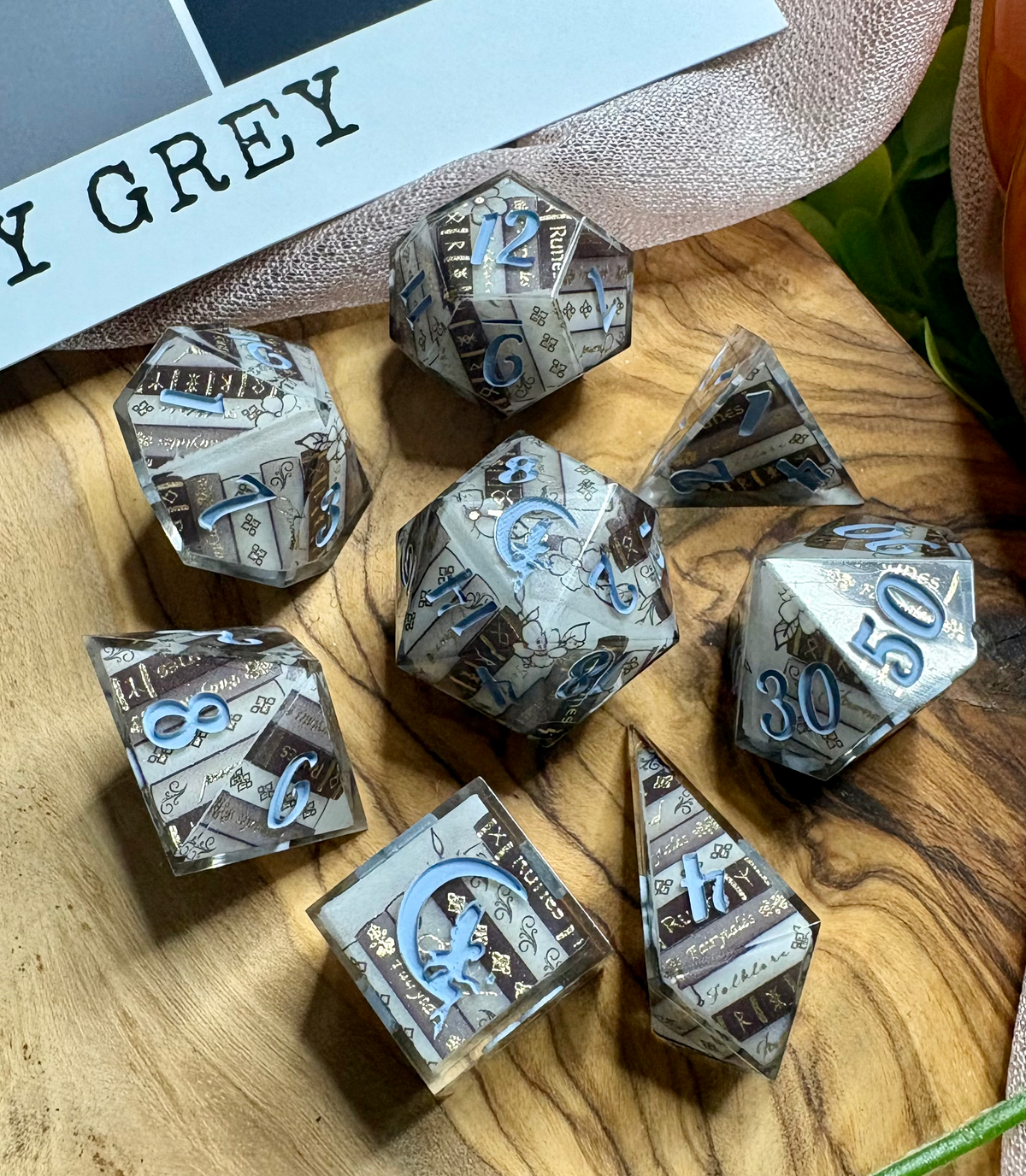 dice set with book decals in grey tones and gold accents