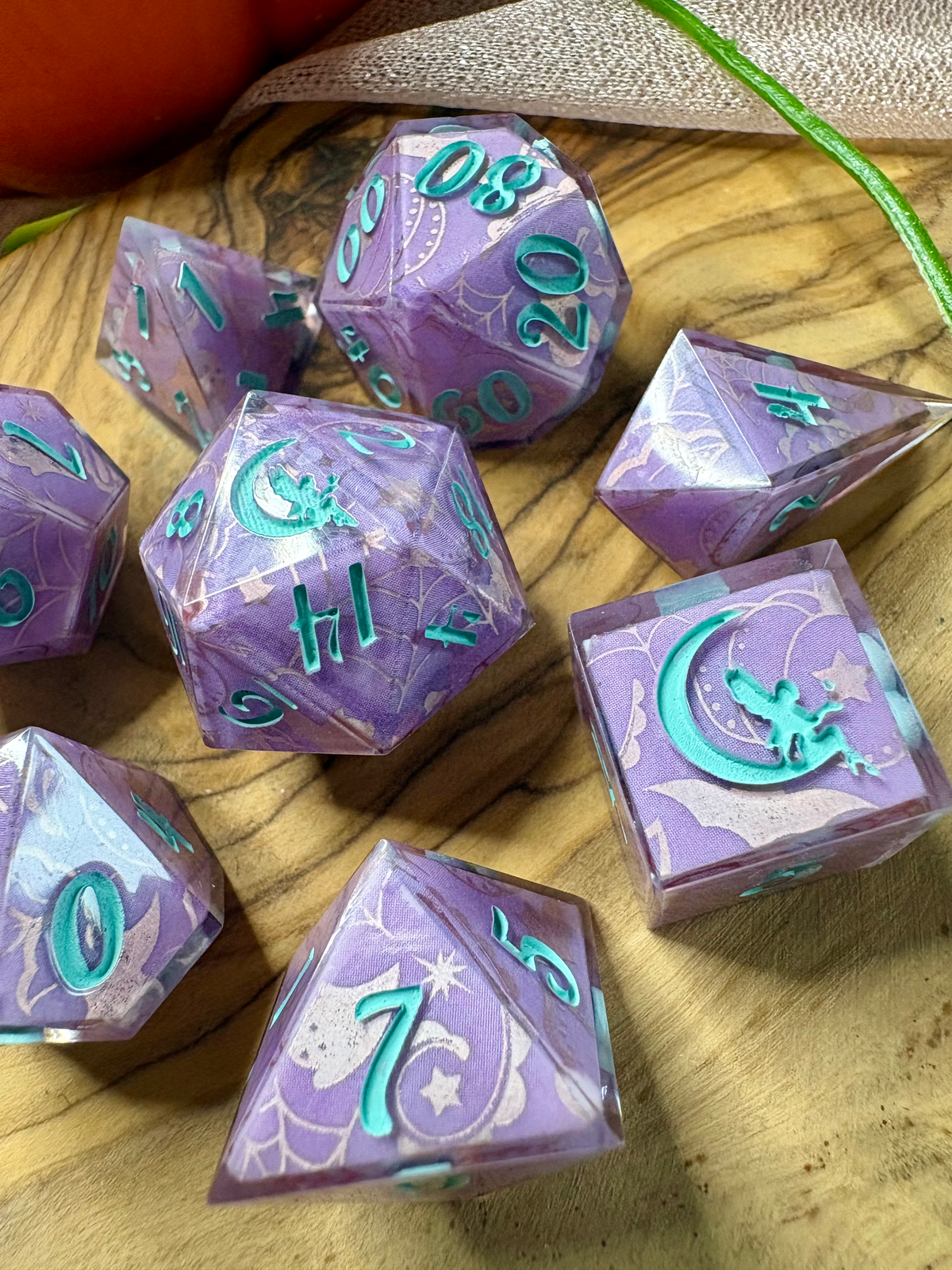 a set of purple polyhedral dice with glittery silver Halloween designs and turquoise ink